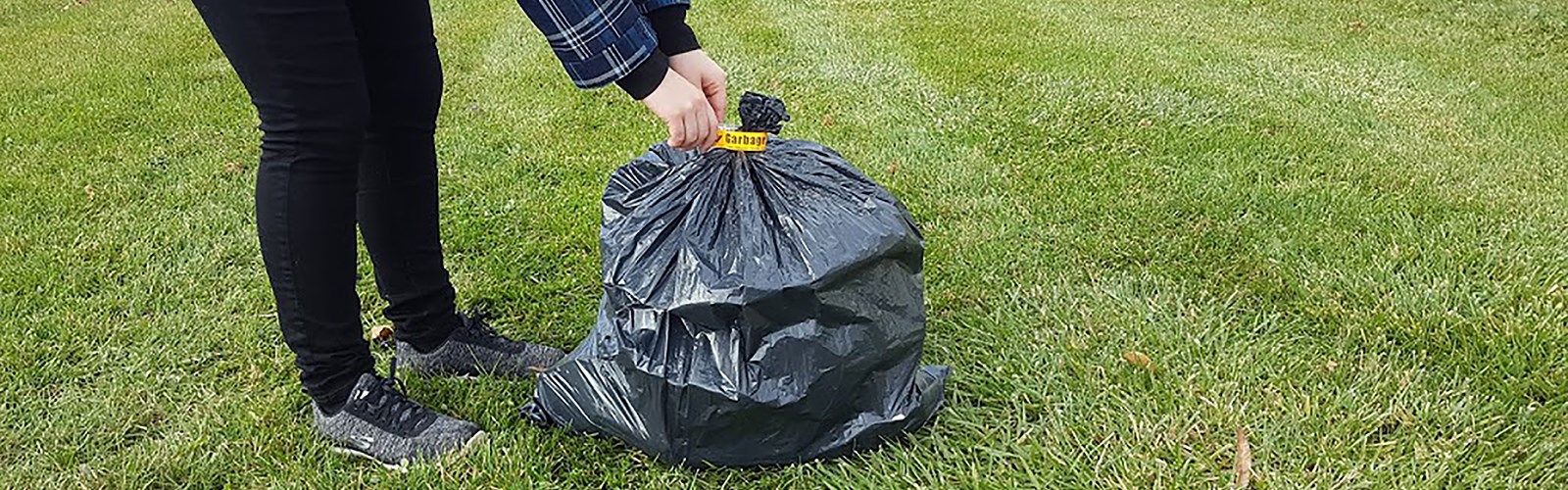 person tying a garbage bag tag on a garbage bag